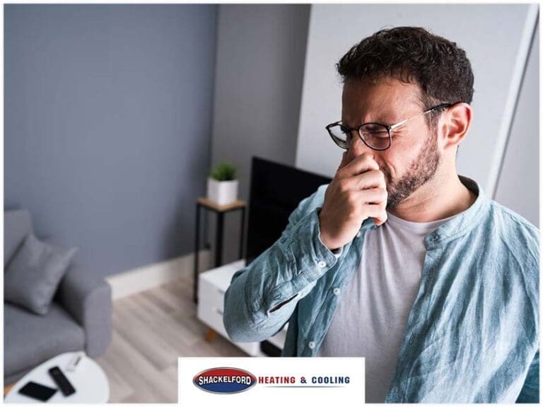 A man holding his nose smelling something that smells like burning