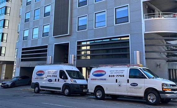 2 service vans parked in front of a high rise apartment building