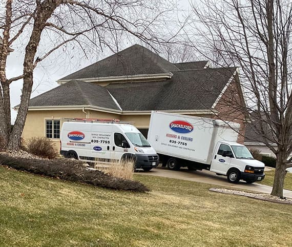 Shackelford van and service truck parked in driveway of a customer