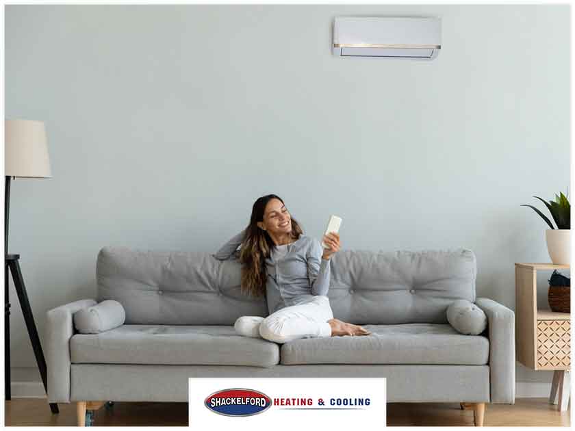 A women on her couch changing the AC with a remote