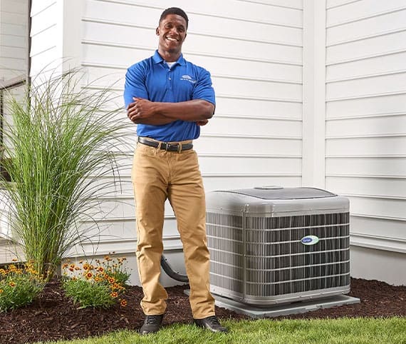 HVAC technician standing smiling next to Air Conditioner unit