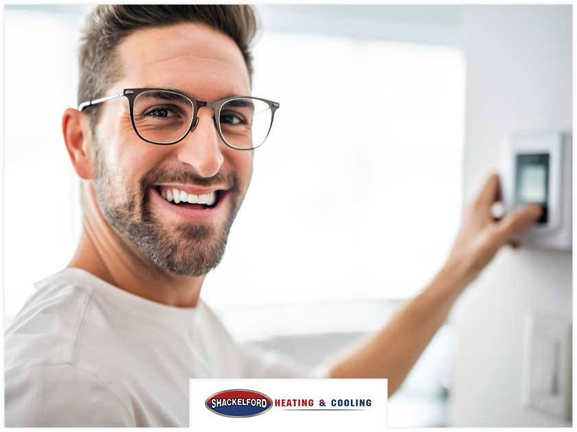 A man looking happy at his new thermostat looking very pleased