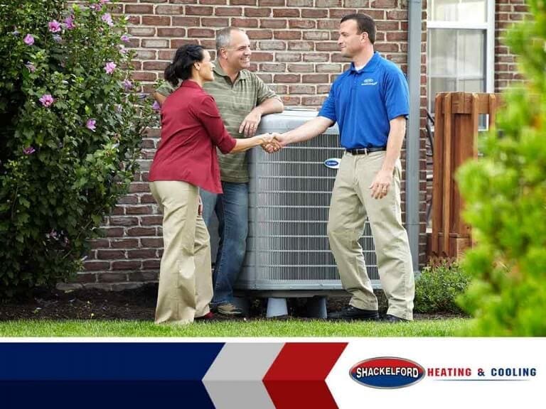A couple thanking a technician after he finished installing a new AC unit for their house