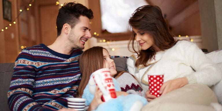 Young family on couch cozy drinking hot chocolate