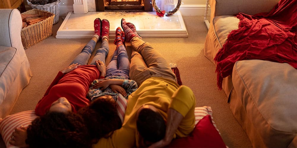 Family laying on floor in front of fireplace